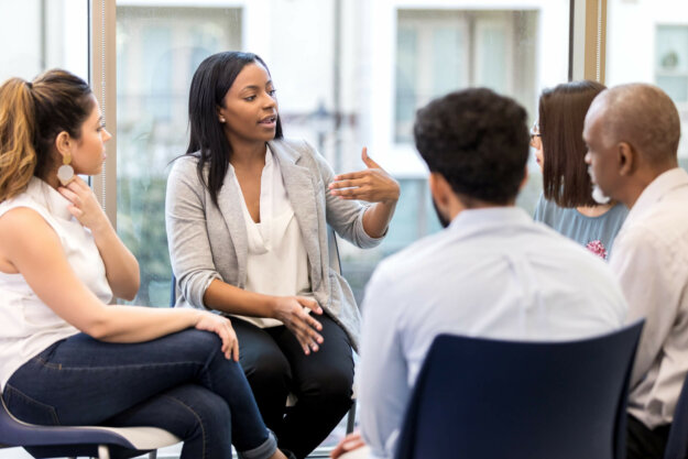 Counselor speaks candidly during group session A young female counselor gestures as she sits in a circle with clients