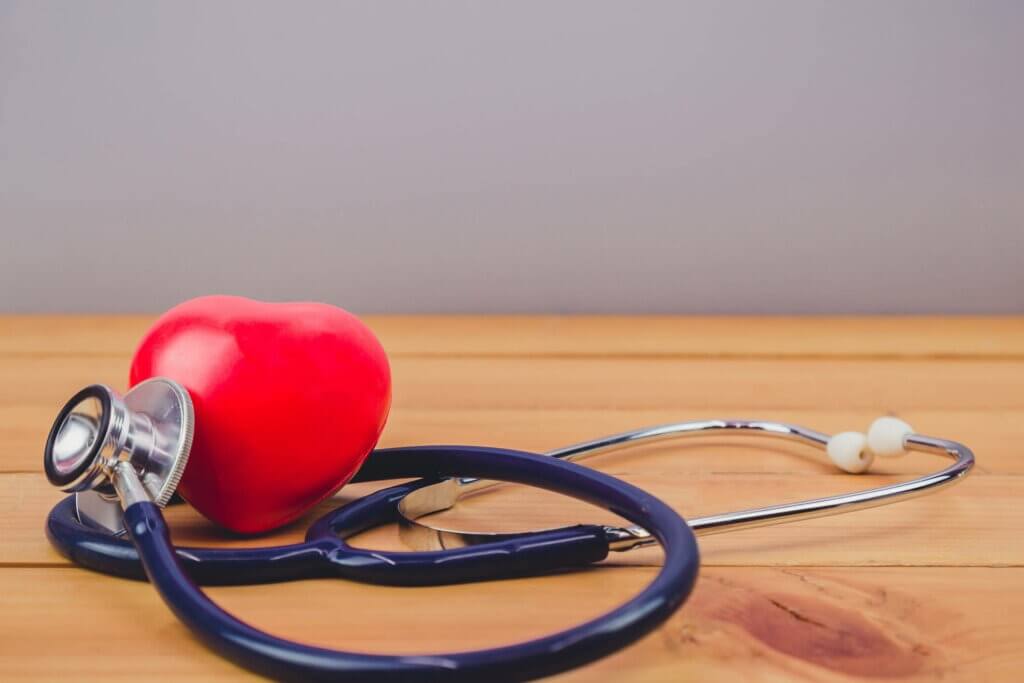 Close up red heart and steythoscope on old wood table and world health day and healthcare technology concept, vintage tone Close up red heart and steythoscope on old wood table